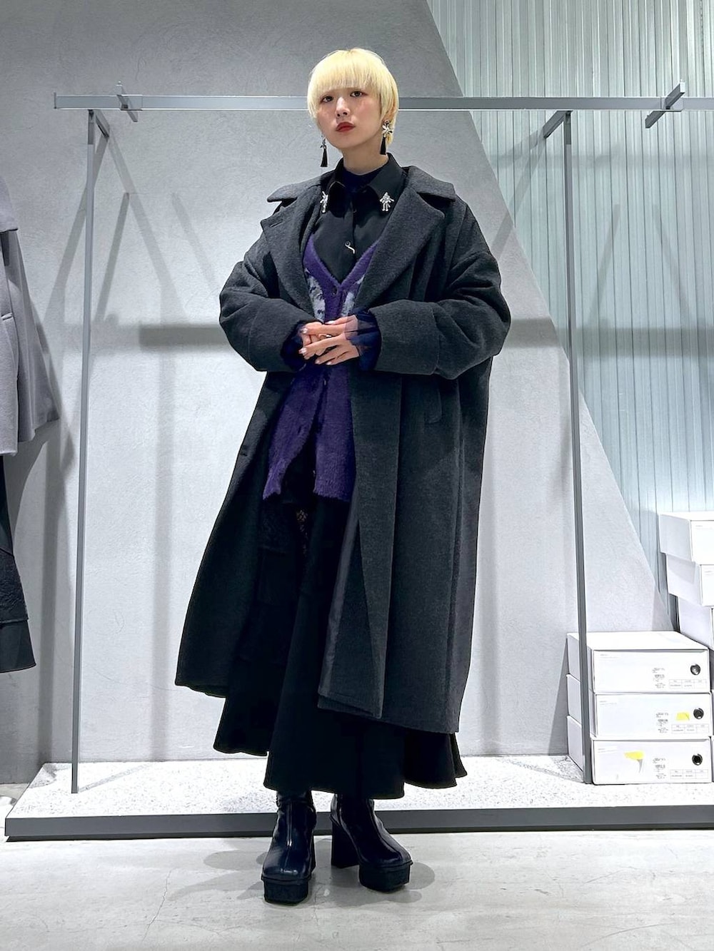 グレー系のチェスターコート、パープル系のカーディガン/ボレロ、グレー系のブーツを着用したレディースの秋コーディネートの2枚目の写真