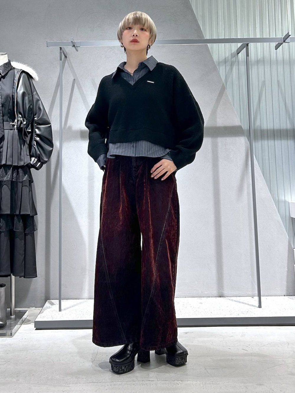 グレー系のチェスターコート、グレー系のブーツ、ブラック系のニット/セーターを着用したレディースの冬コーディネートの2枚目の写真