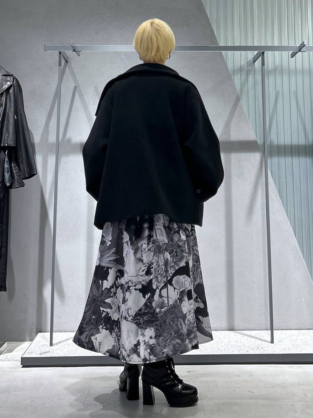 ブラック系のチェスターコート、ブラック系のブーツ、ホワイト系のスカートを着用したレディースの秋コーディネートの6枚目の写真