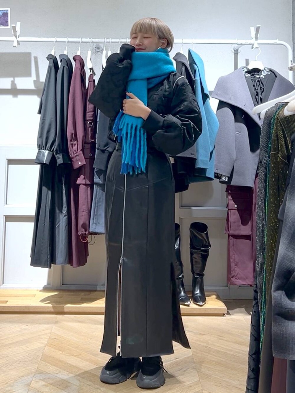 ブラック系のブルゾン、ブラック系のスカート、ブルー系のマフラーを着用したレディースの秋コーディネートの2枚目の写真