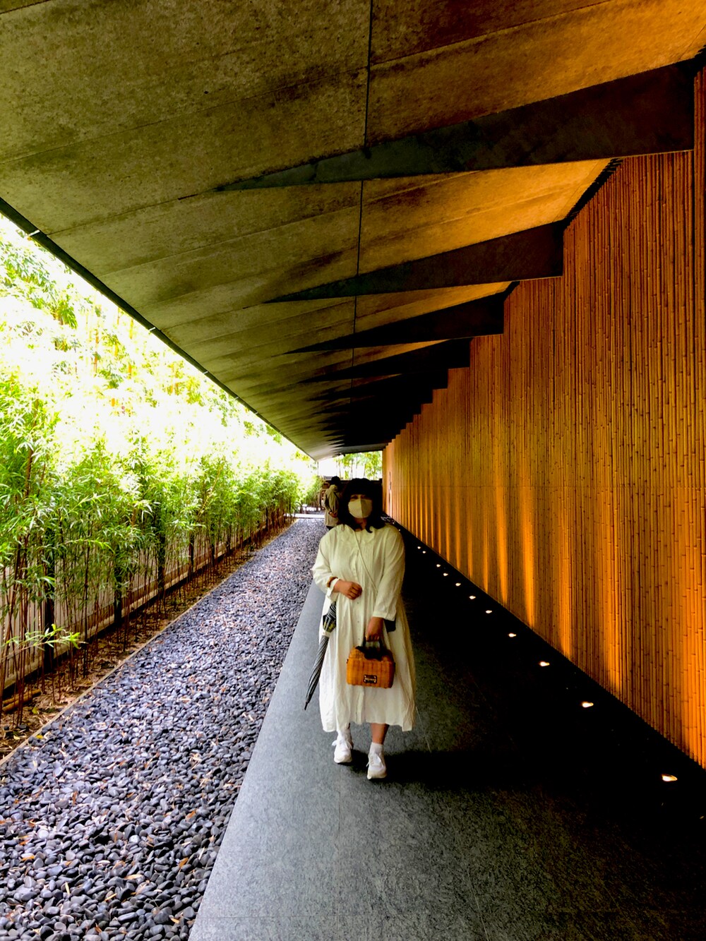 ブラウン系のかごバッグ、ホワイト系のワンピース、ベージュ系のスニーカーを着用したレディースの春コーディネートの2枚目の写真