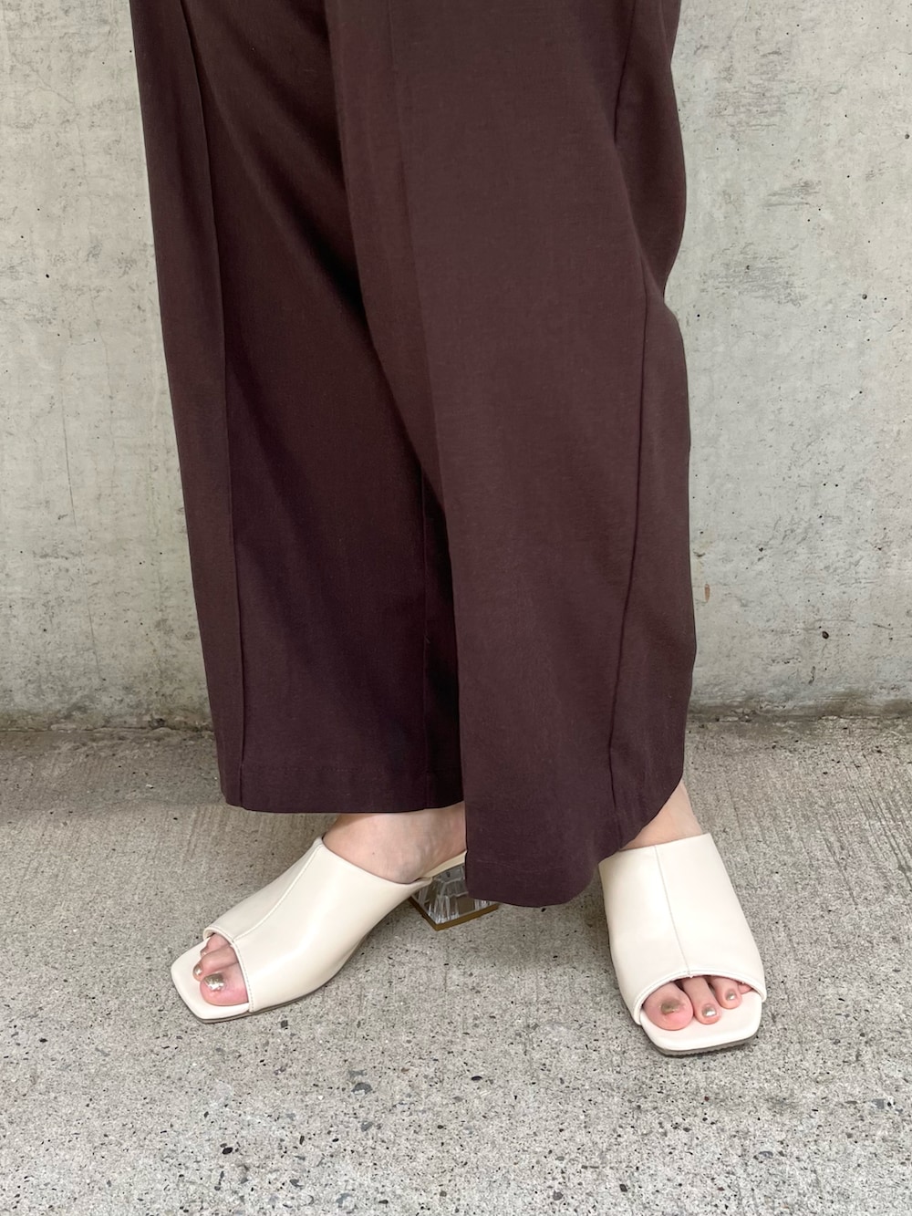 ブラウン系のその他パンツ、ベージュ系のニット/セーター、ホワイト系のサンダルを着用したレディースの夏コーディネートの3枚目の写真