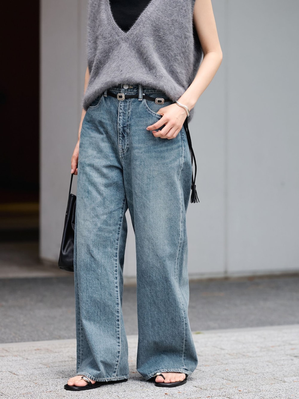 ブルー系のデニムパンツ、グレー系のベスト、ブラック系のハンドバッグを着用したレディースの夏コーディネートの7枚目の写真