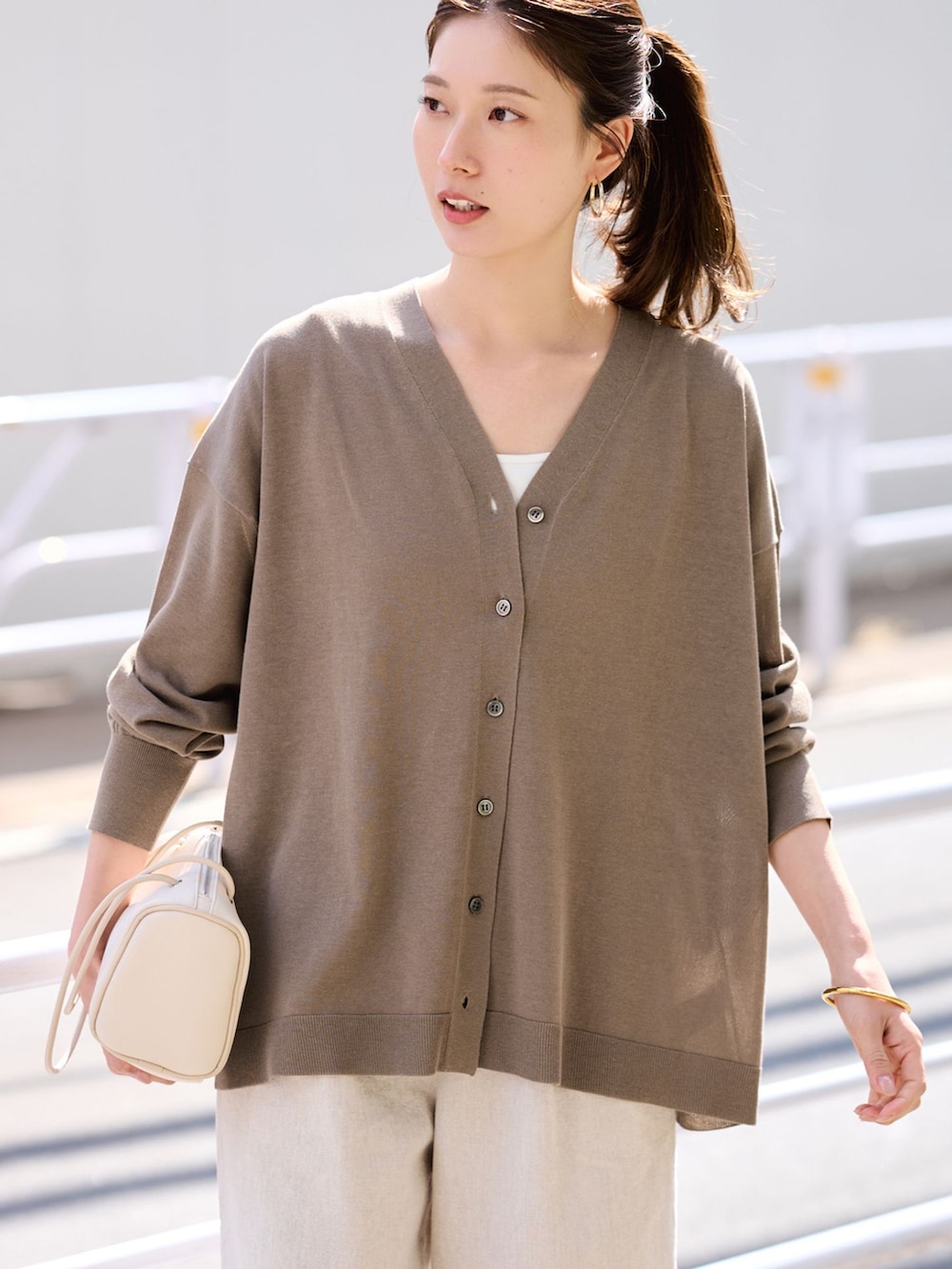 ベージュ系のその他パンツ、ブラウン系のカーディガン/ボレロ、ホワイト系のボストンバッグを着用したレディースの春コーディネートの4枚目の写真