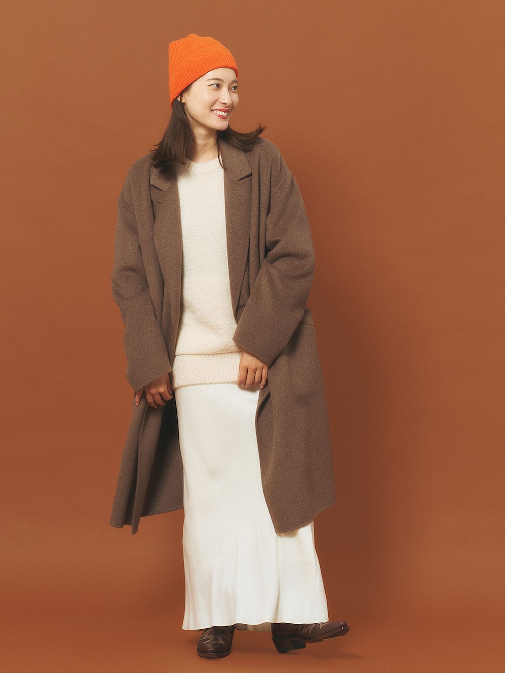 ブラウン系のチェスターコート、ホワイト系のスカート、ホワイト系のニット/セーターを着用したレディースの冬コーディネートの2枚目の写真