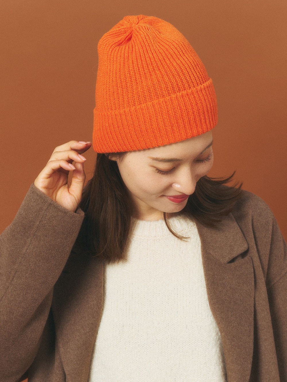 ブラウン系のチェスターコート、ホワイト系のスカート、ホワイト系のニット/セーターを着用したレディースの冬コーディネートの5枚目の写真