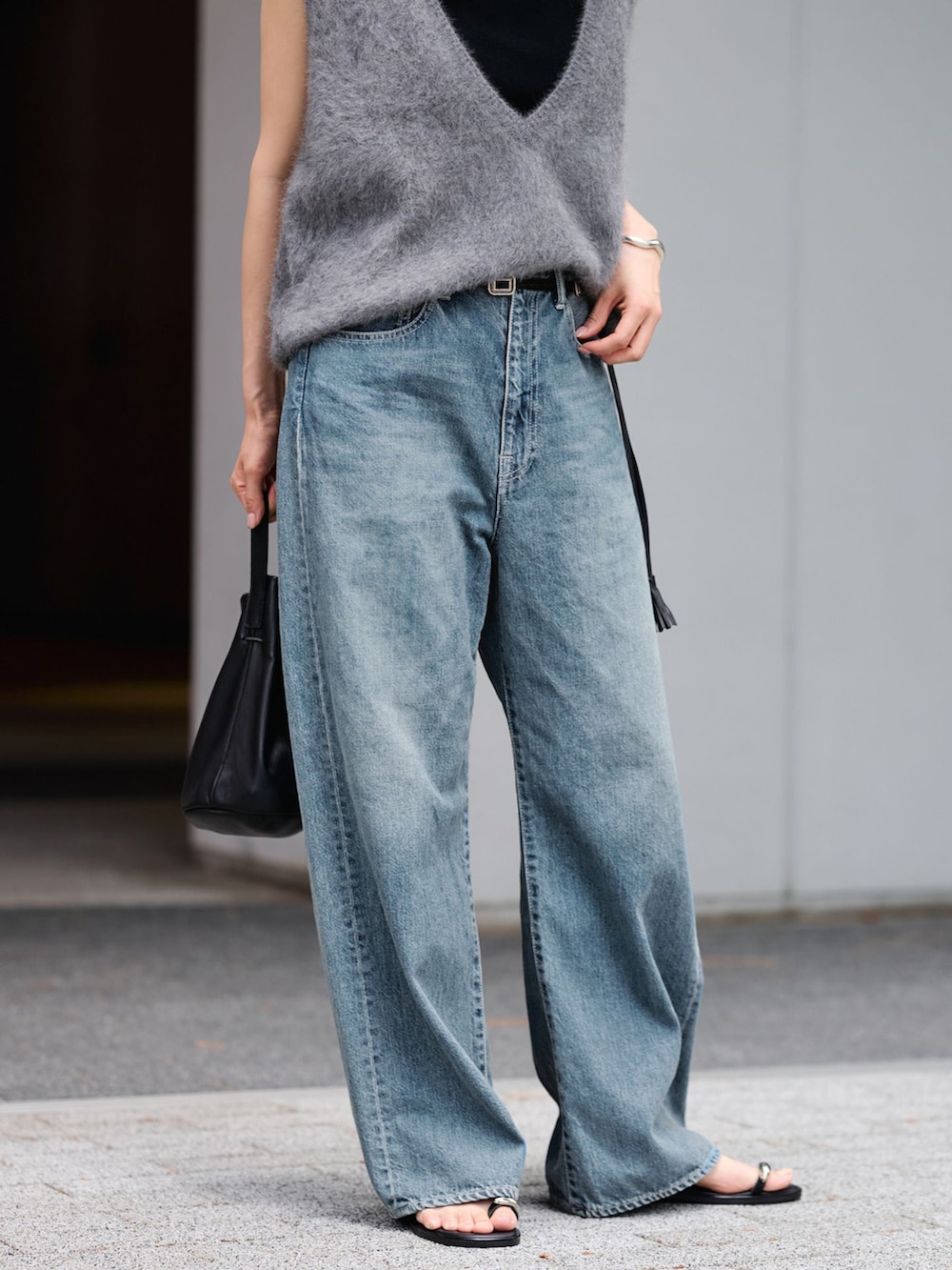 ブルー系のデニムパンツ、グレー系のベスト、ブラック系のハンドバッグを着用したレディースの夏コーディネートの5枚目の写真
