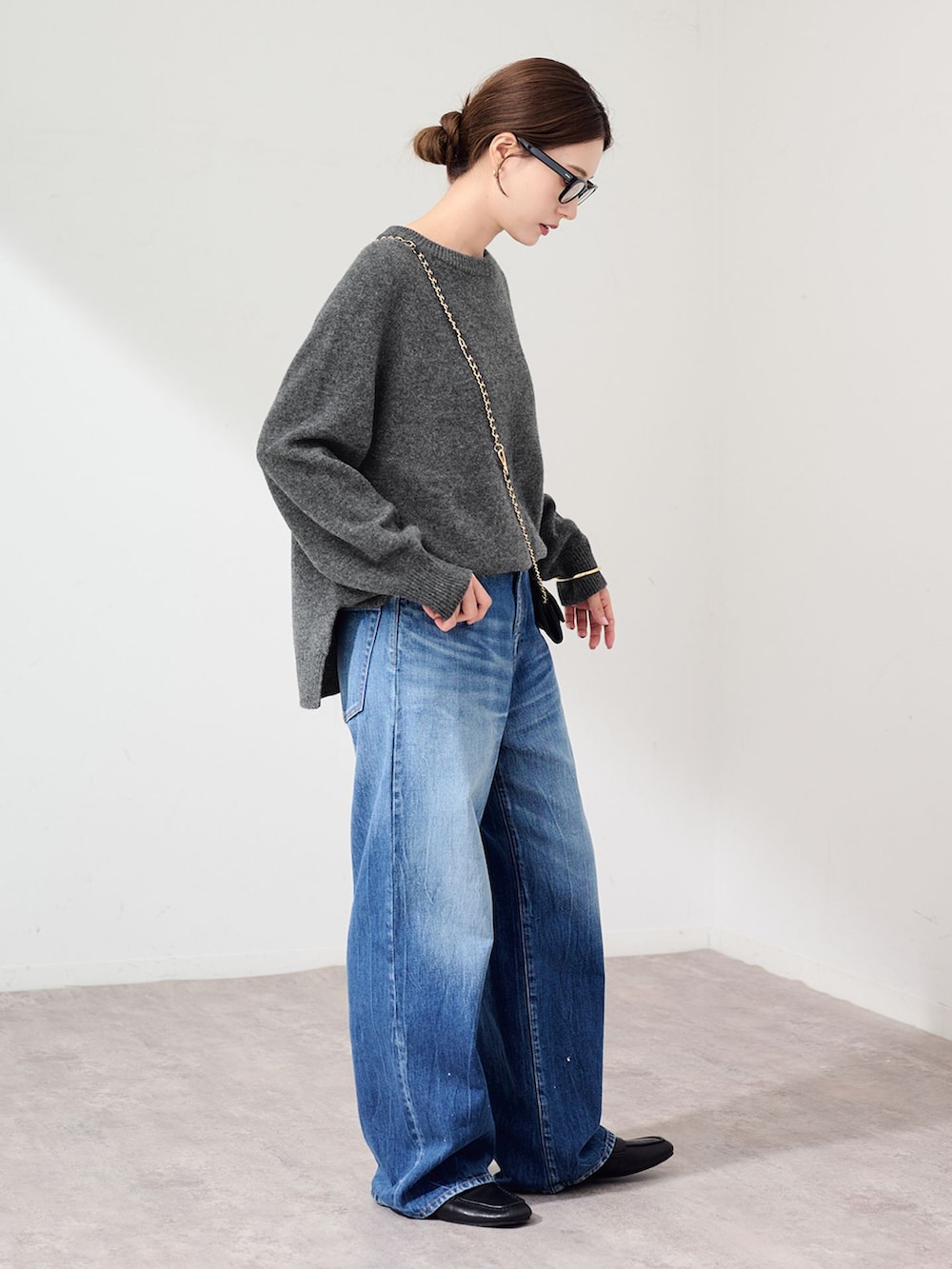 ブルー系のデニムパンツ、グレー系のニット/セーター、ブラック系のスリッポンを着用したレディースの秋コーディネートの2枚目の写真