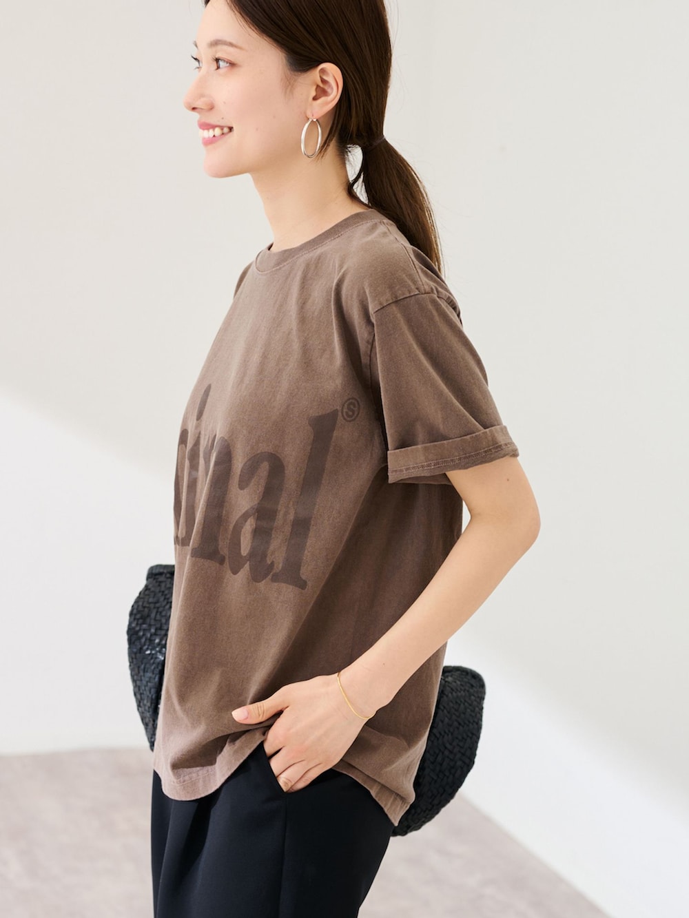 ブラック系のスラックス、ブラウン系のTシャツ/カットソー、ブラック系のトートバッグを着用したレディースの春コーディネートの5枚目の写真