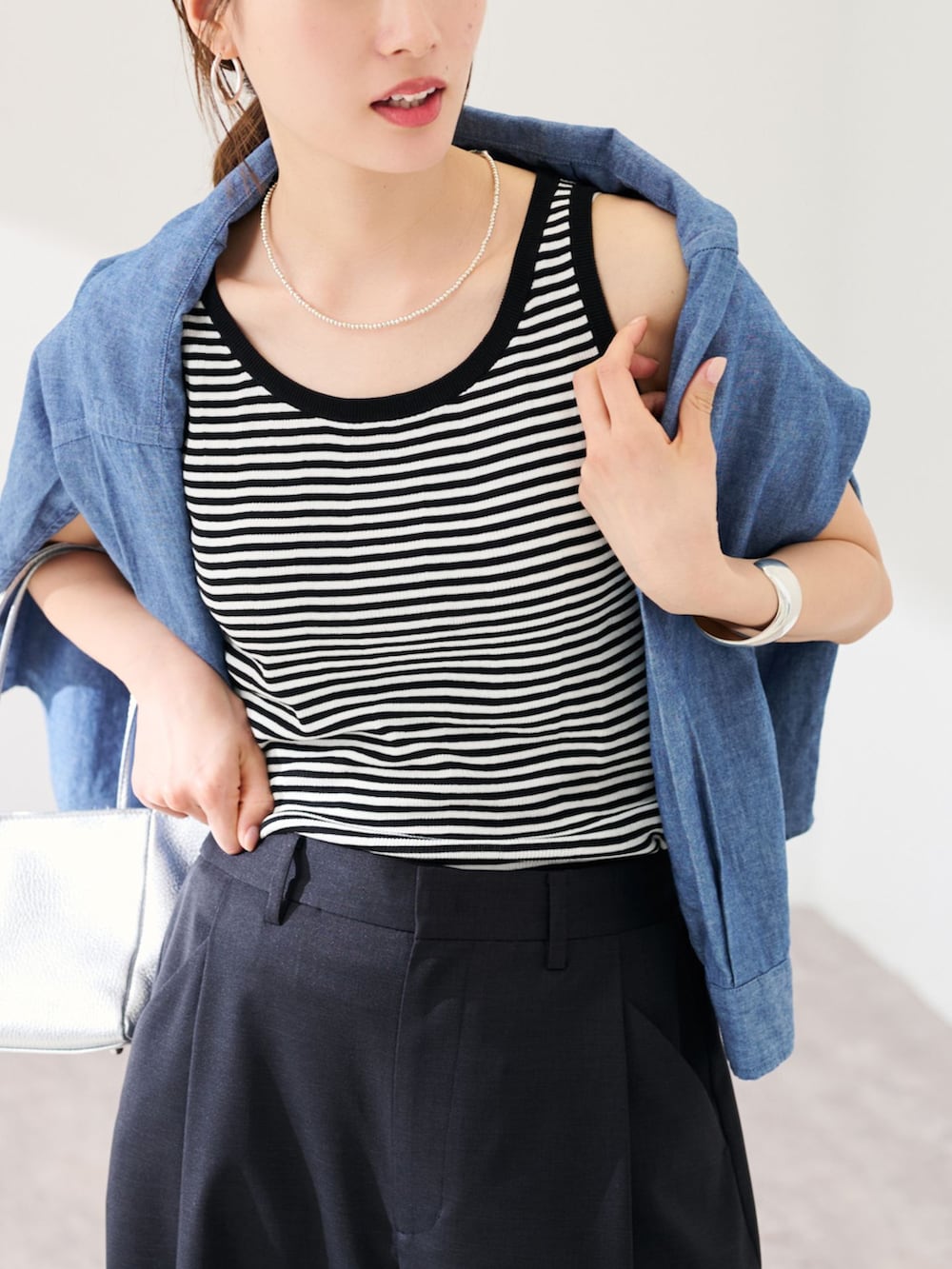 ブラック系のスラックス、ブルー系のシャツ/ブラウス、ホワイト系のタンクトップを着用したレディースの春コーディネートの4枚目の写真