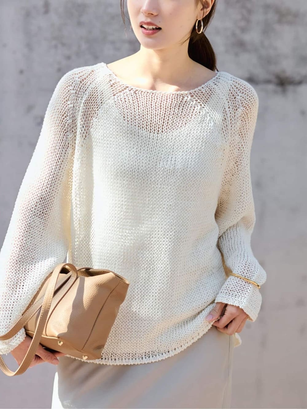 ベージュ系のスカート、ホワイト系のニット/セーターを着用したレディースの春コーディネートの3枚目の写真