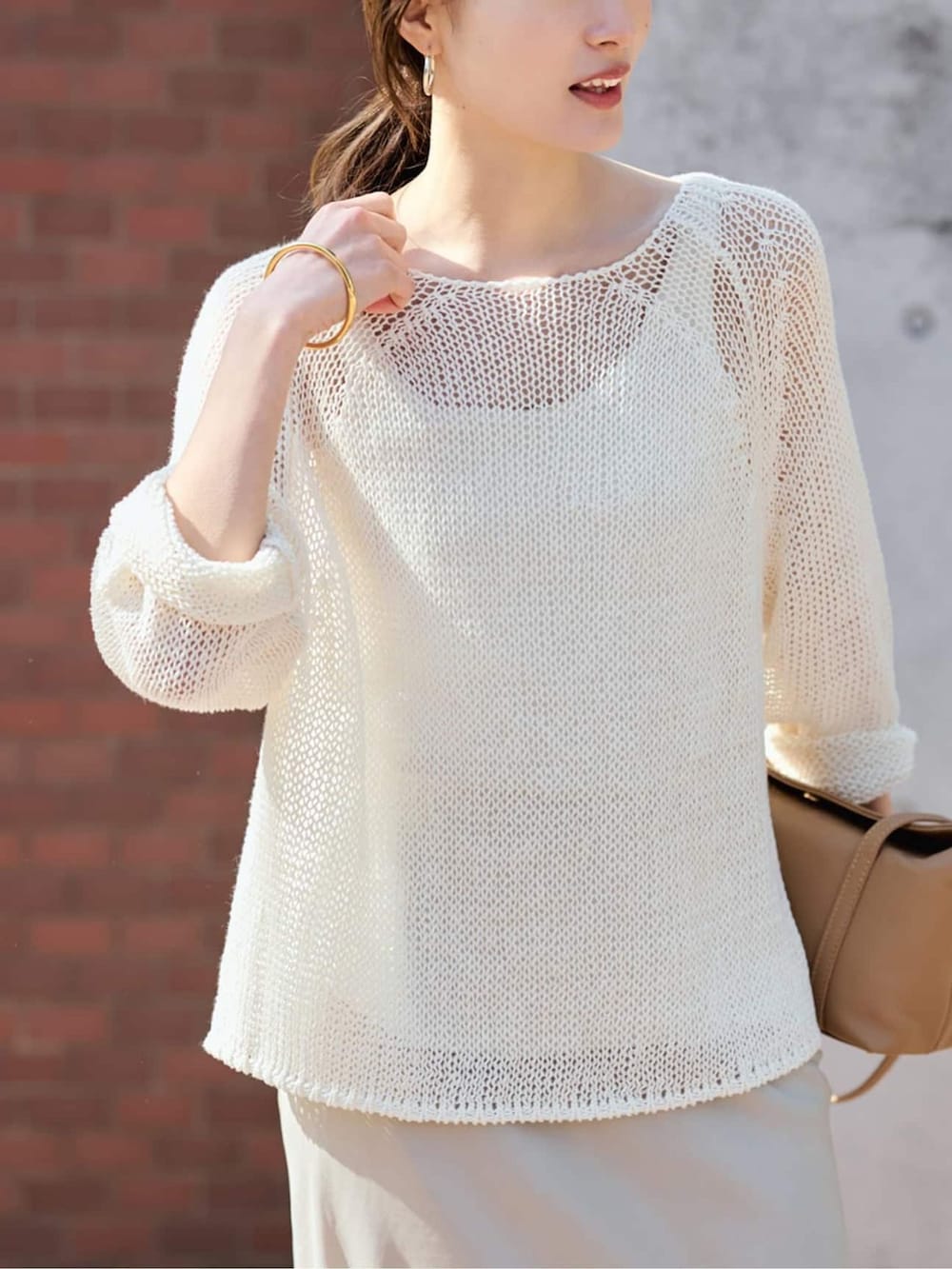 ベージュ系のスカート、ホワイト系のニット/セーターを着用したレディースの春コーディネートの4枚目の写真