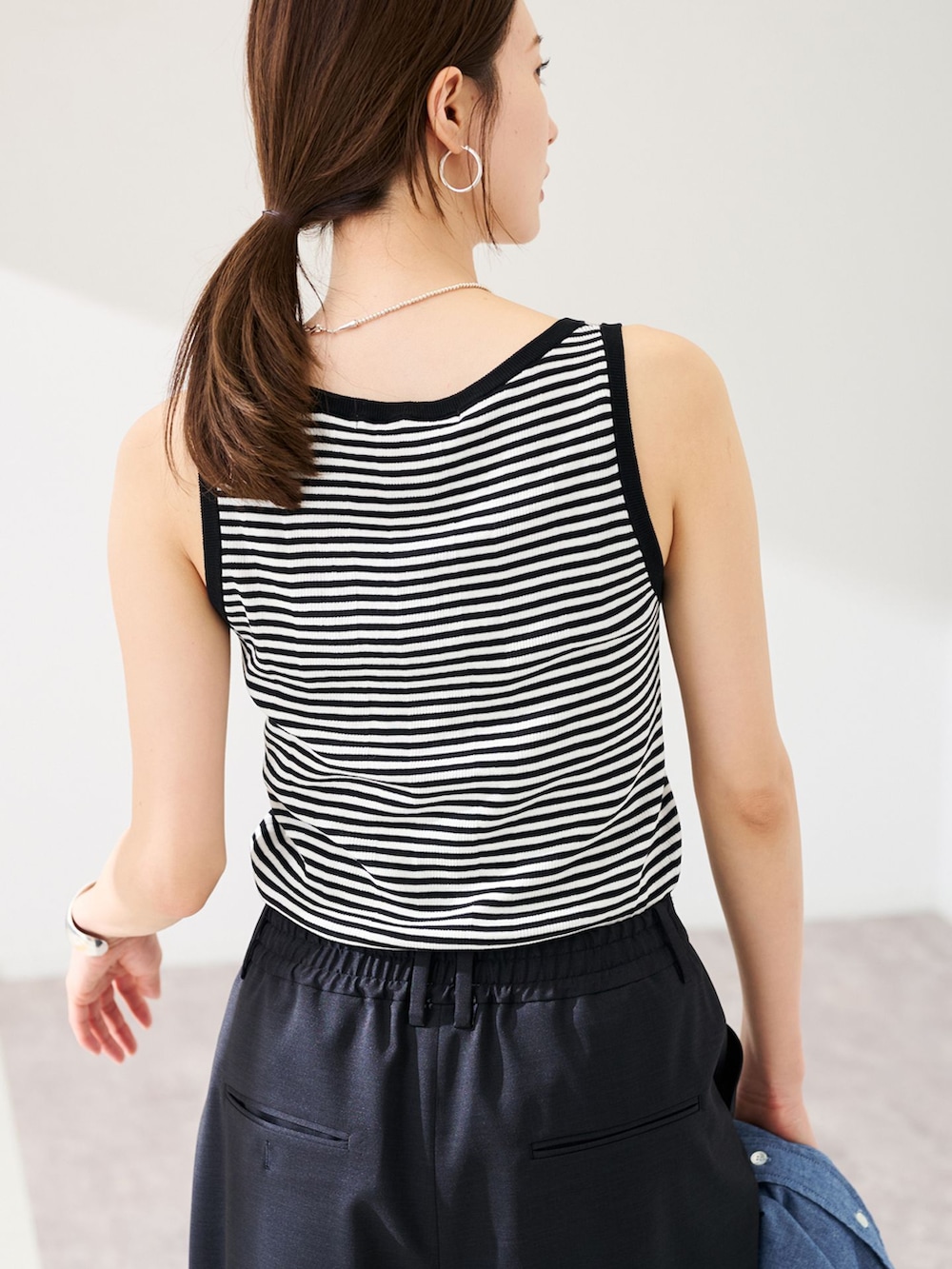 ブラック系のスラックス、ブルー系のシャツ/ブラウス、ホワイト系のタンクトップを着用したレディースの春コーディネートの7枚目の写真