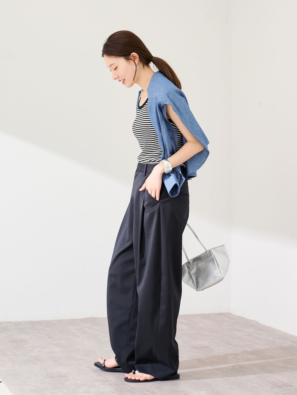 ブラック系のスラックス、ブルー系のシャツ/ブラウス、ホワイト系のタンクトップを着用したレディースの春コーディネートの2枚目の写真