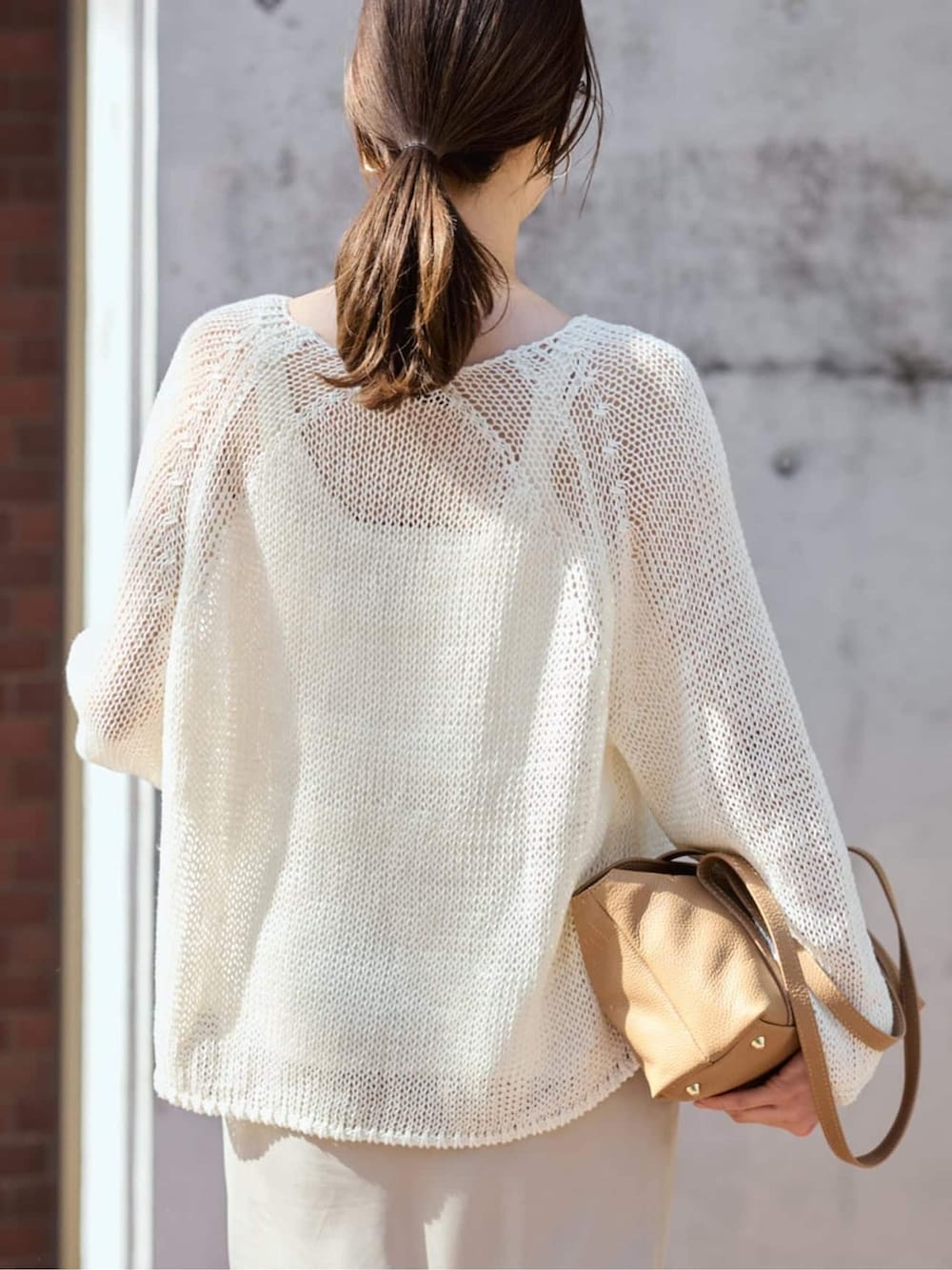 ベージュ系のスカート、ホワイト系のニット/セーターを着用したレディースの春コーディネートの6枚目の写真