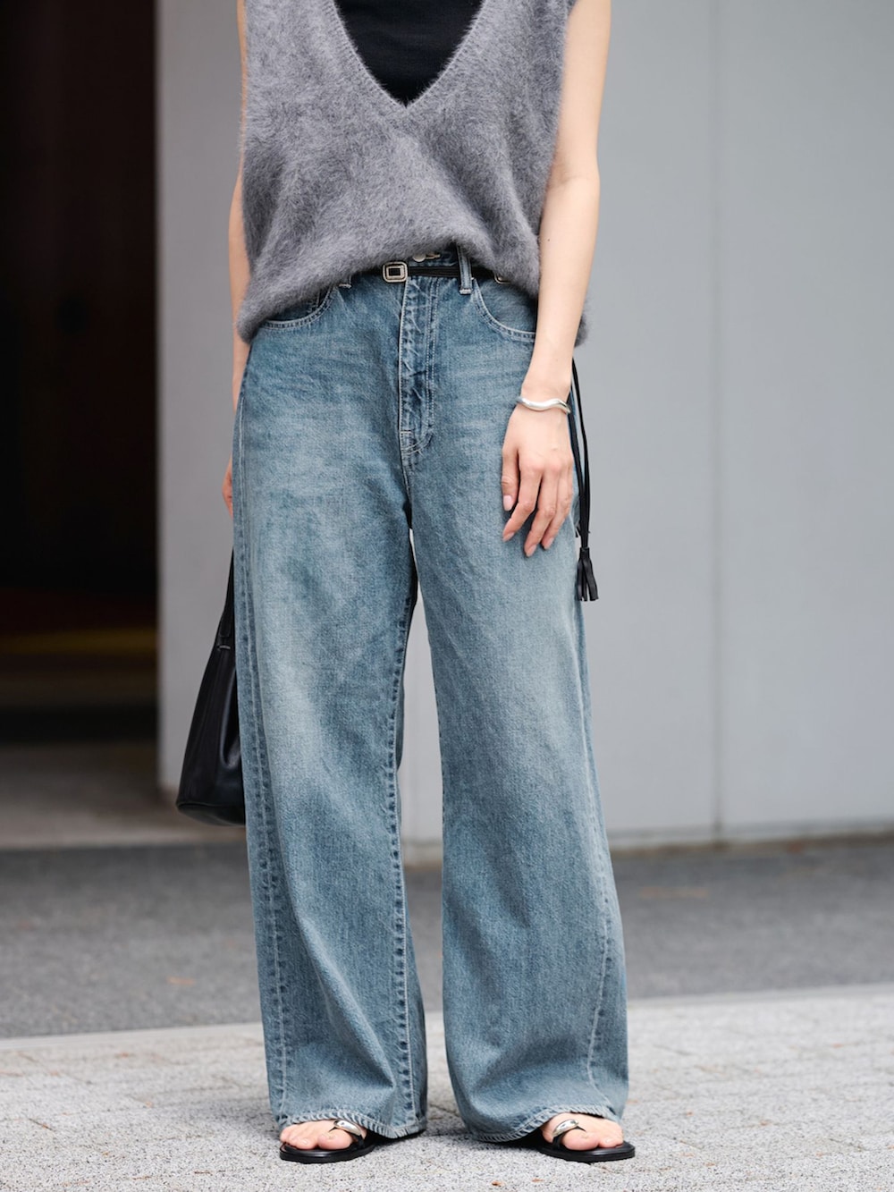 ブルー系のデニムパンツ、グレー系のベスト、ブラック系のハンドバッグを着用したレディースの夏コーディネートの6枚目の写真