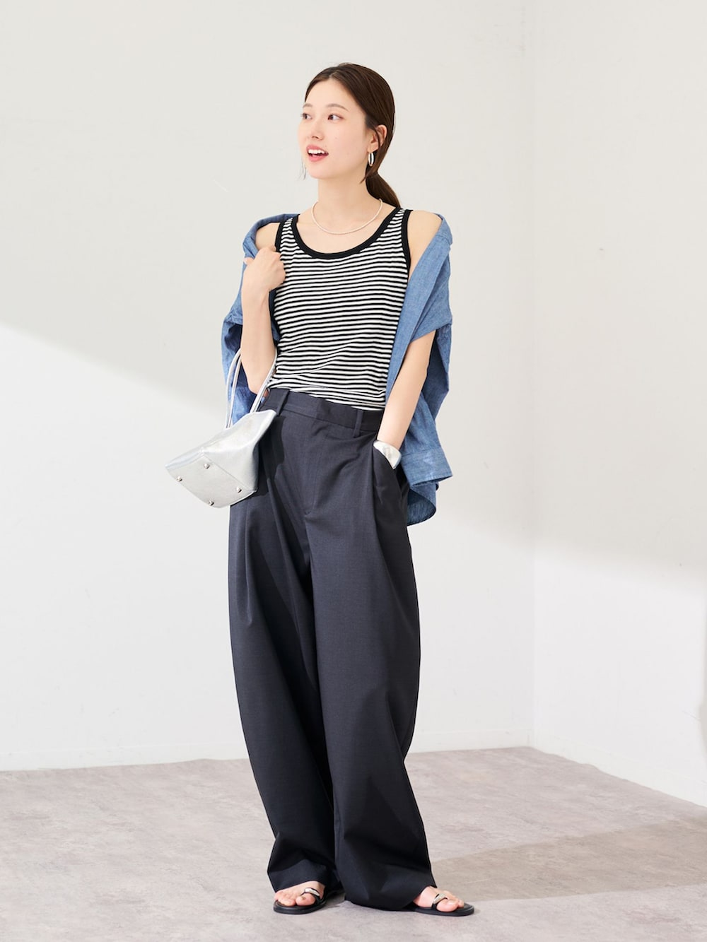 ブラック系のスラックス、ブルー系のシャツ/ブラウス、ホワイト系のタンクトップを着用したレディースの春コーディネートの3枚目の写真