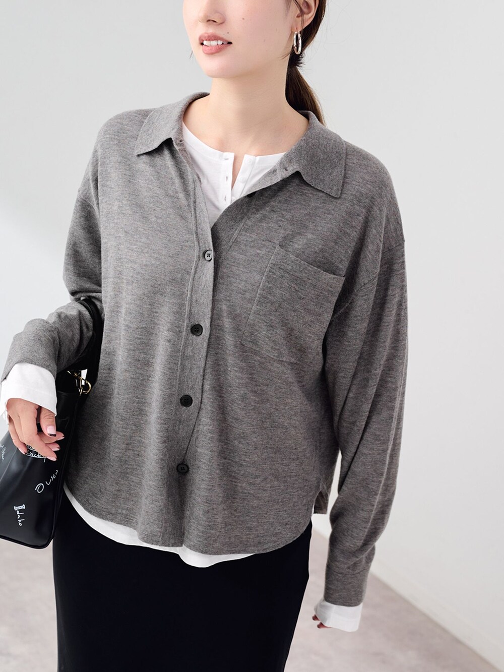 ブラック系のスカート、ホワイト系のTシャツ/カットソー、グレー系のニット/セーターを着用したレディースの秋コーディネートの4枚目の写真