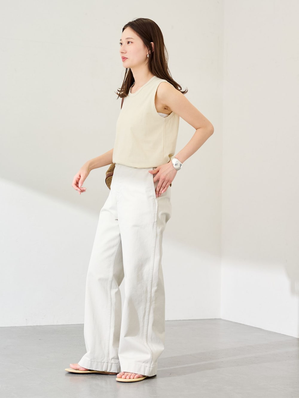 ホワイト系のチノパンツ、イエロー系のTシャツ/カットソー、ベージュ系のバックパック/リュックを着用したレディースの春コーディネートの2枚目の写真