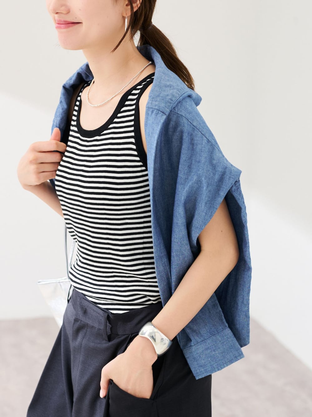 ブラック系のスラックス、ブルー系のシャツ/ブラウス、ホワイト系のタンクトップを着用したレディースの春コーディネートの5枚目の写真