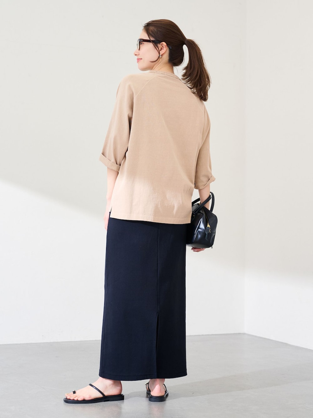 ブラック系のスカート、ベージュ系のTシャツ/カットソー、ブラック系のショルダーバッグを着用したレディースの冬コーディネートの2枚目の写真