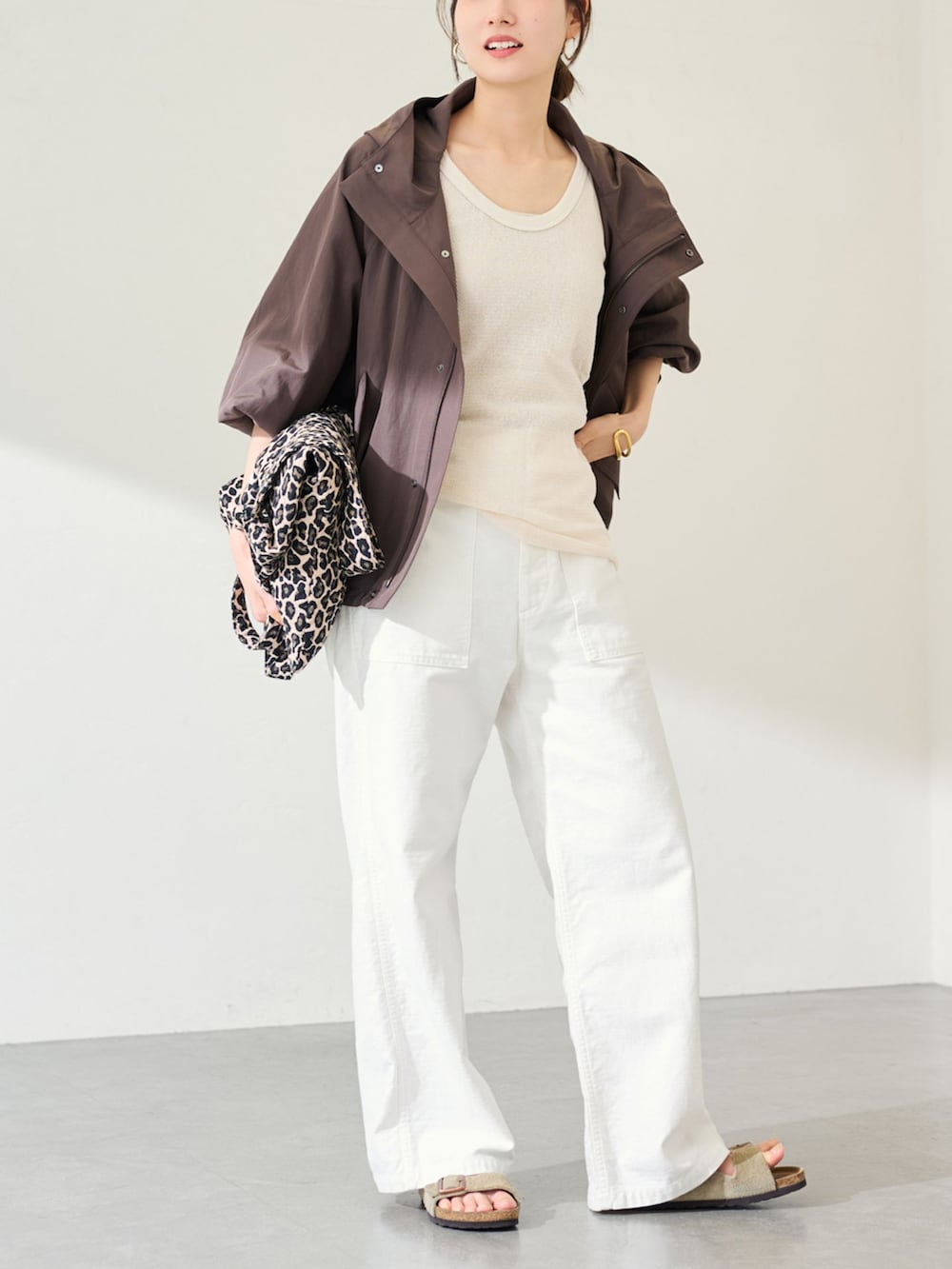 ホワイト系のカーゴパンツ、ブラウン系のマウンテンパーカー、ホワイト系のタンクトップを着用したレディースの冬コーディネートの2枚目の写真