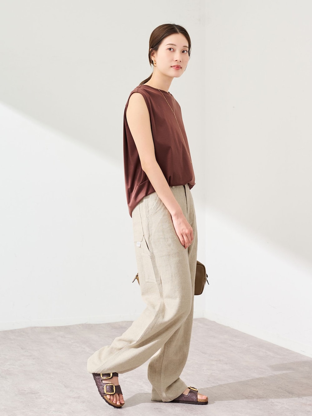 ベージュ系のデニムパンツ、ブラウン系のTシャツ/カットソー、ブラウン系のショルダーバッグを着用したレディースの夏コーディネートの2枚目の写真