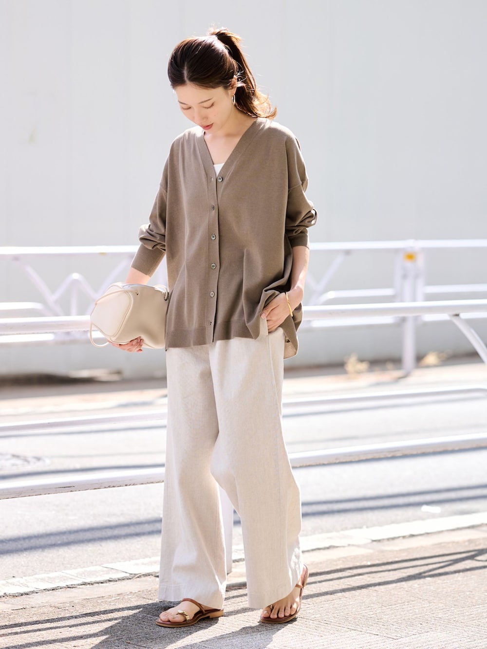 ベージュ系のその他パンツ、ブラウン系のカーディガン/ボレロ、ホワイト系のボストンバッグを着用したレディースの春コーディネートの2枚目の写真