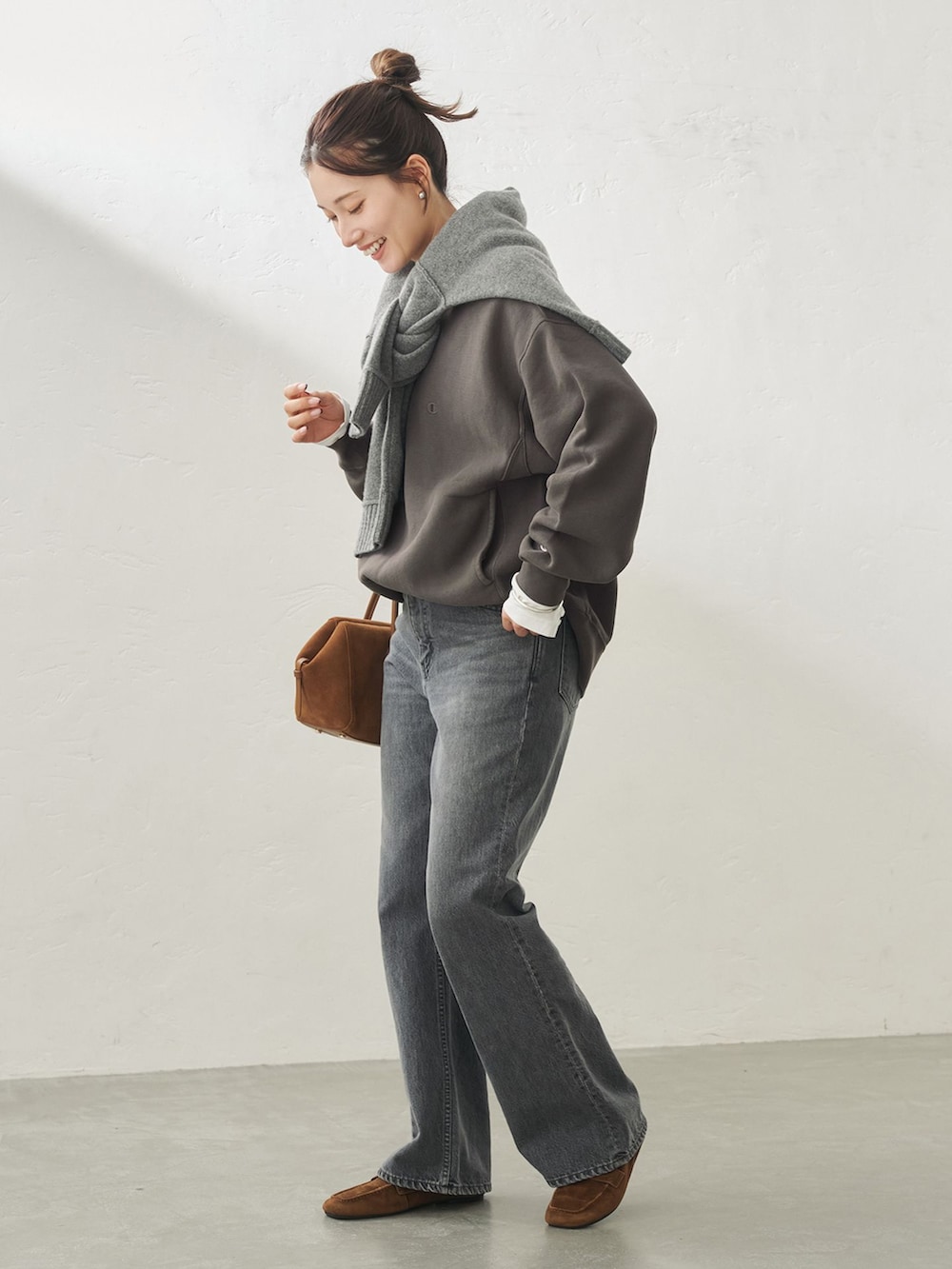 ブラック系のデニムパンツ、ホワイト系のTシャツ/カットソー、ブラック系のスウェットを着用したレディースの秋コーディネートの2枚目の写真