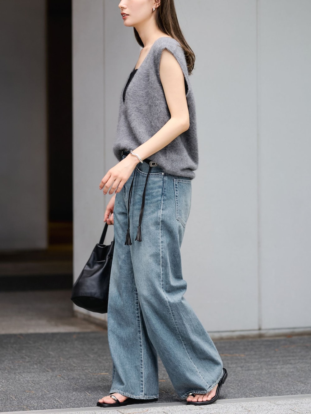 ブルー系のデニムパンツ、グレー系のベスト、ブラック系のハンドバッグを着用したレディースの夏コーディネートの2枚目の写真