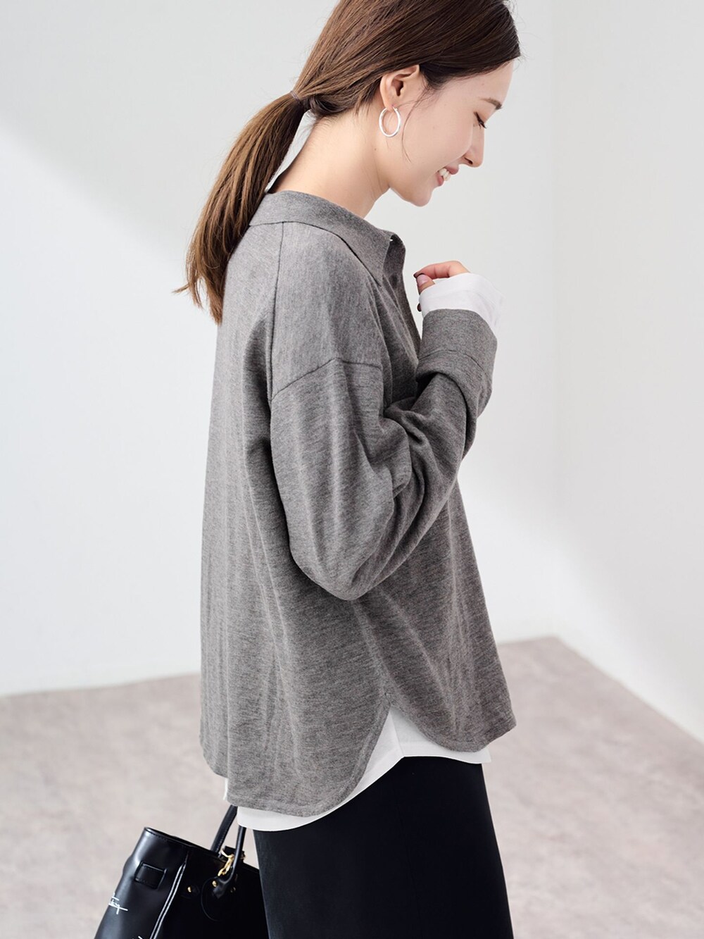 ブラック系のスカート、ホワイト系のTシャツ/カットソー、グレー系のニット/セーターを着用したレディースの秋コーディネートの7枚目の写真
