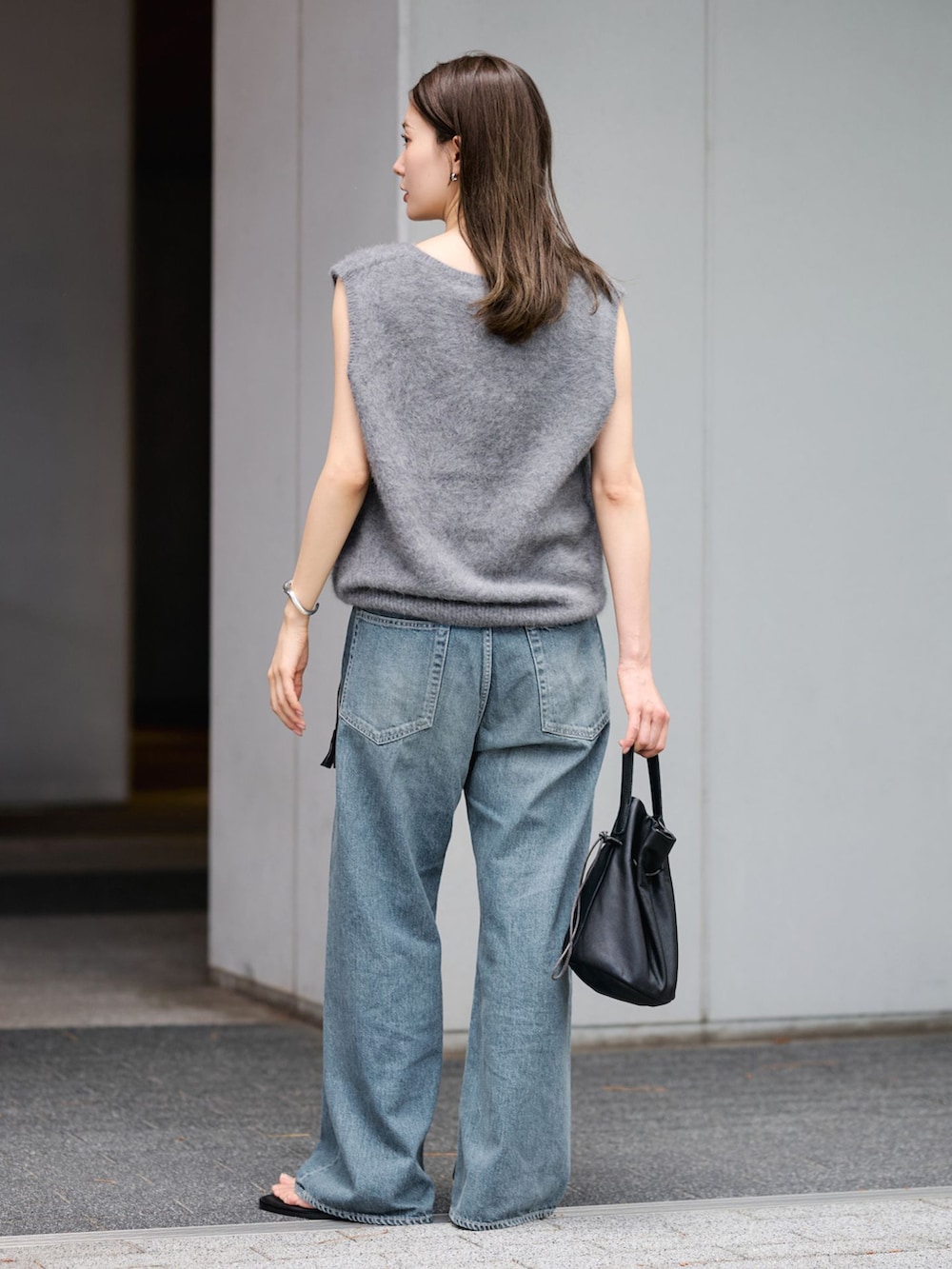 ブルー系のデニムパンツ、グレー系のベスト、ブラック系のハンドバッグを着用したレディースの夏コーディネートの3枚目の写真