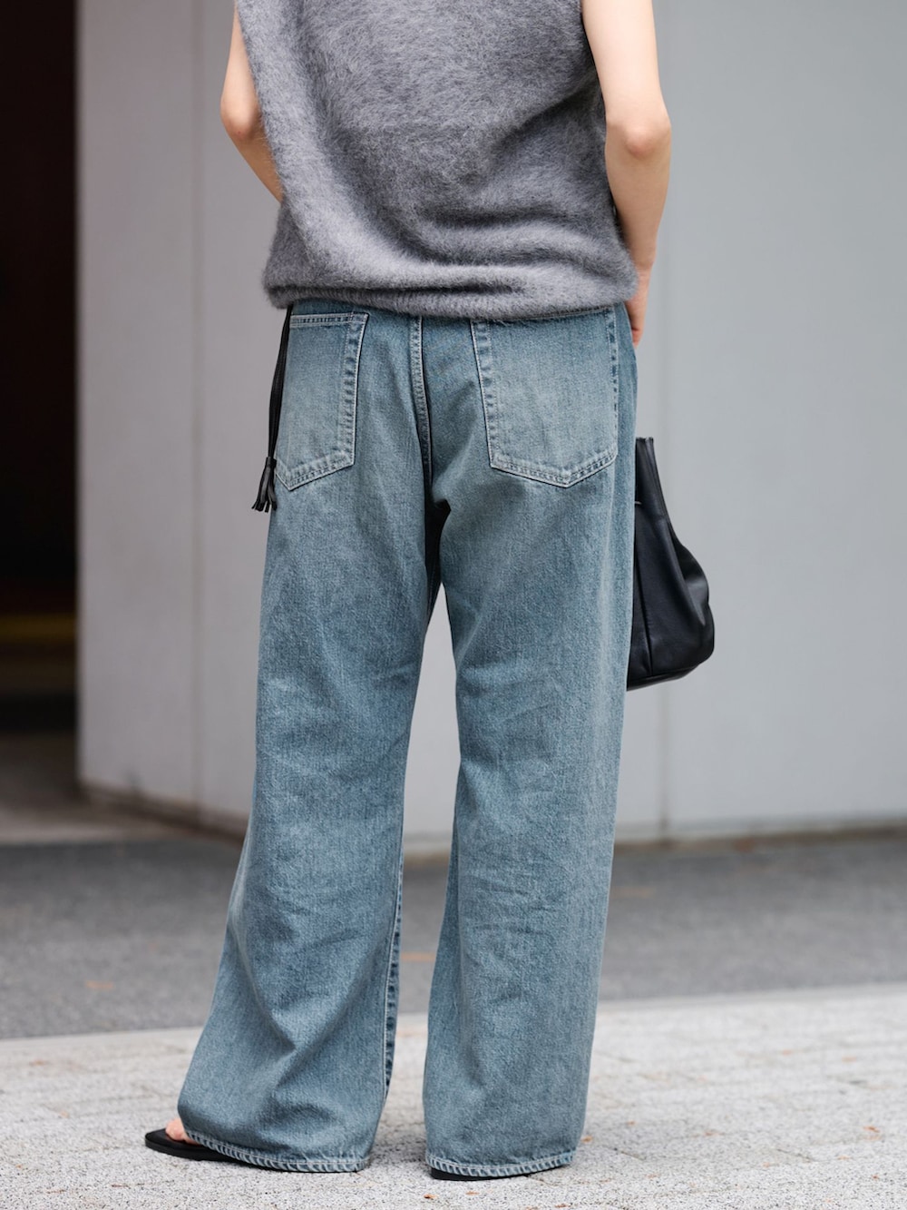 ブルー系のデニムパンツ、グレー系のベスト、ブラック系のハンドバッグを着用したレディースの夏コーディネートの4枚目の写真