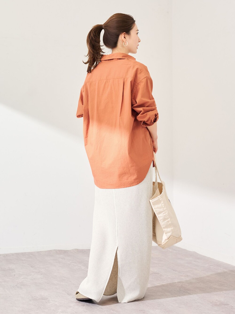 ブラウン系のシャツ/ブラウス、グレー系のスカート、ホワイト系のトートバッグを着用したレディースの冬コーディネートの2枚目の写真