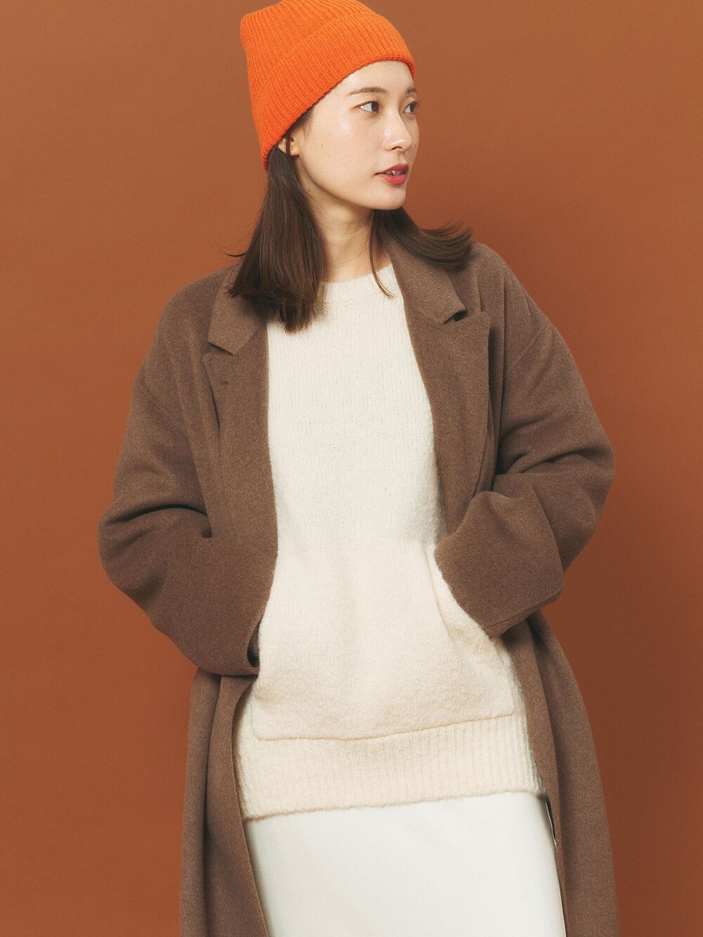 ブラウン系のチェスターコート、ホワイト系のスカート、ホワイト系のニット/セーターを着用したレディースの冬コーディネートの4枚目の写真