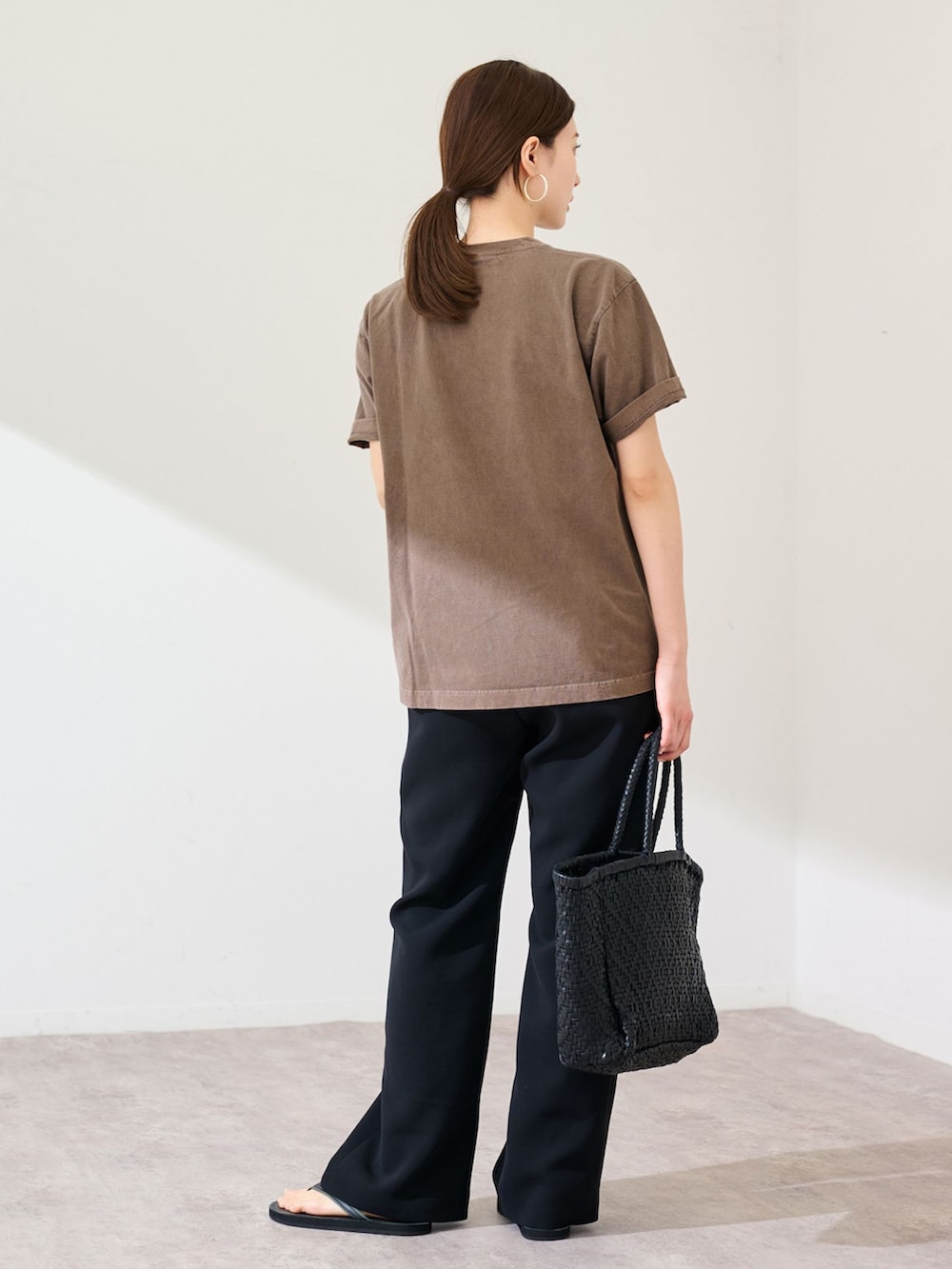 ブラック系のスラックス、ブラウン系のTシャツ/カットソー、ブラック系のトートバッグを着用したレディースの春コーディネートの3枚目の写真