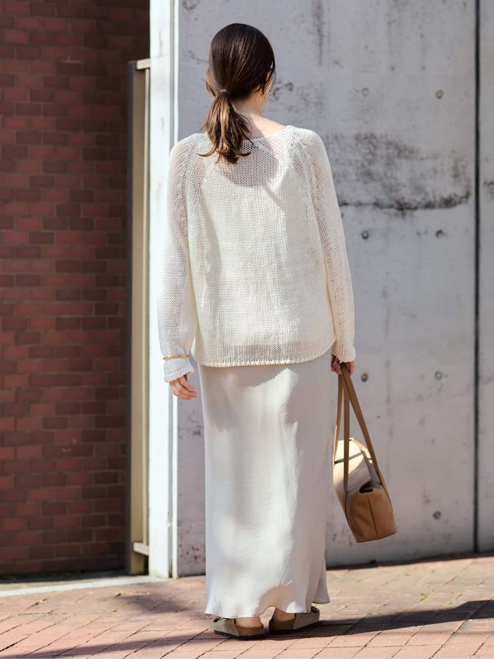 ベージュ系のスカート、ホワイト系のニット/セーターを着用したレディースの春コーディネートの2枚目の写真
