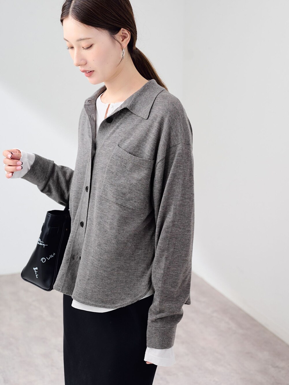 ブラック系のスカート、ホワイト系のTシャツ/カットソー、グレー系のニット/セーターを着用したレディースの秋コーディネートの5枚目の写真
