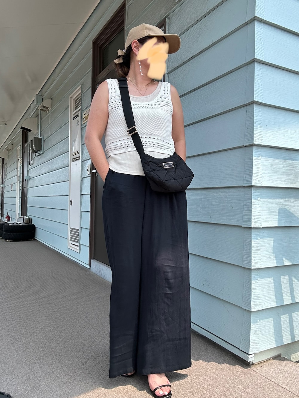 ホワイト系のタンクトップ、ブラック系のショルダーバッグ、ブラック系のパンツを着用したレディースの夏コーディネートの2枚目の写真