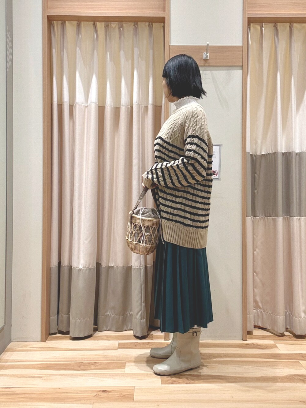ベージュ系のニット/セーター、ベージュ系のハンドバッグ、グリーン系のスカートを着用したレディースの冬コーディネートの2枚目の写真