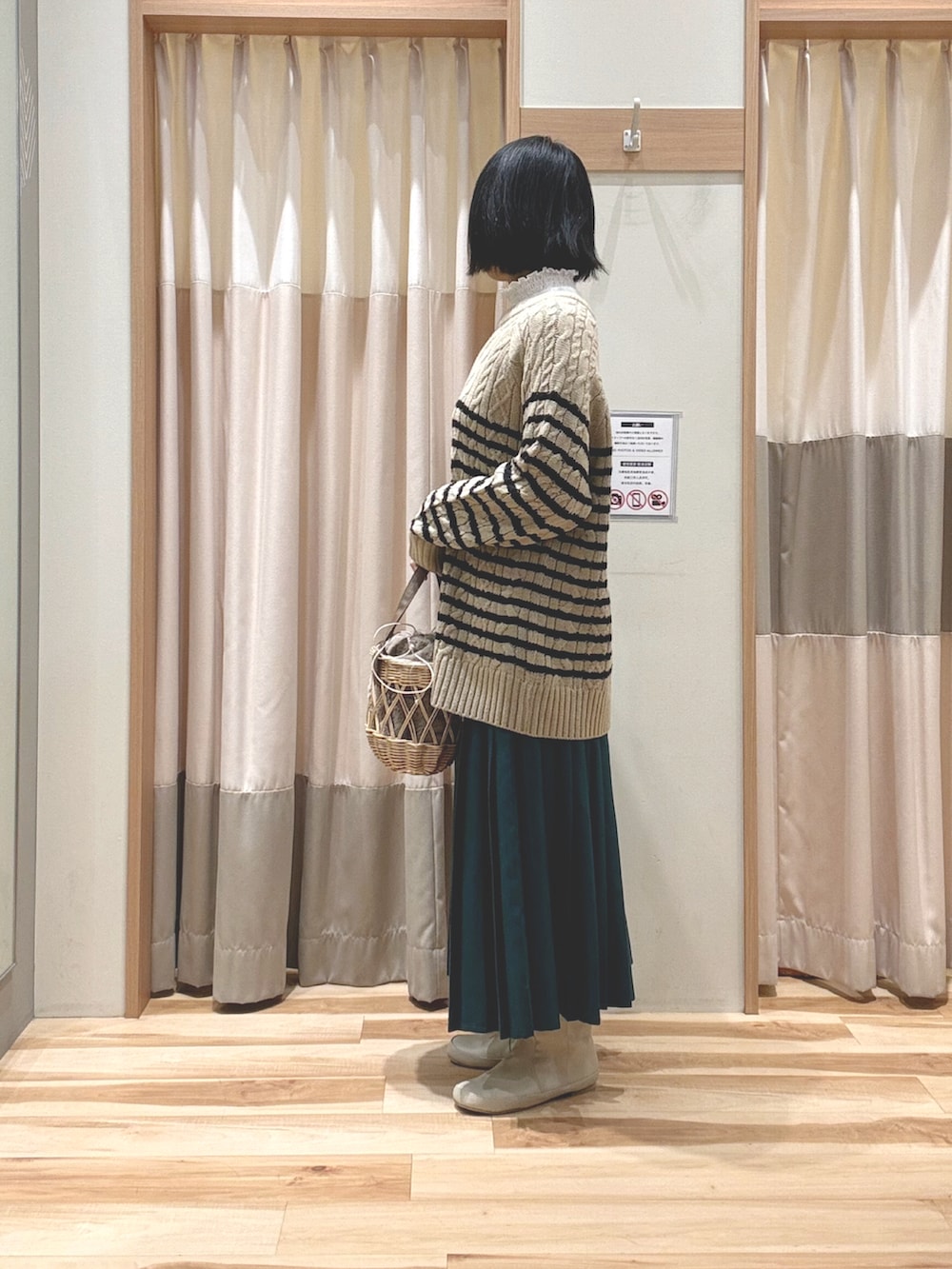 ベージュ系のニット/セーター、ベージュ系のハンドバッグ、グリーン系のスカートを着用したレディースの冬コーディネートの4枚目の写真