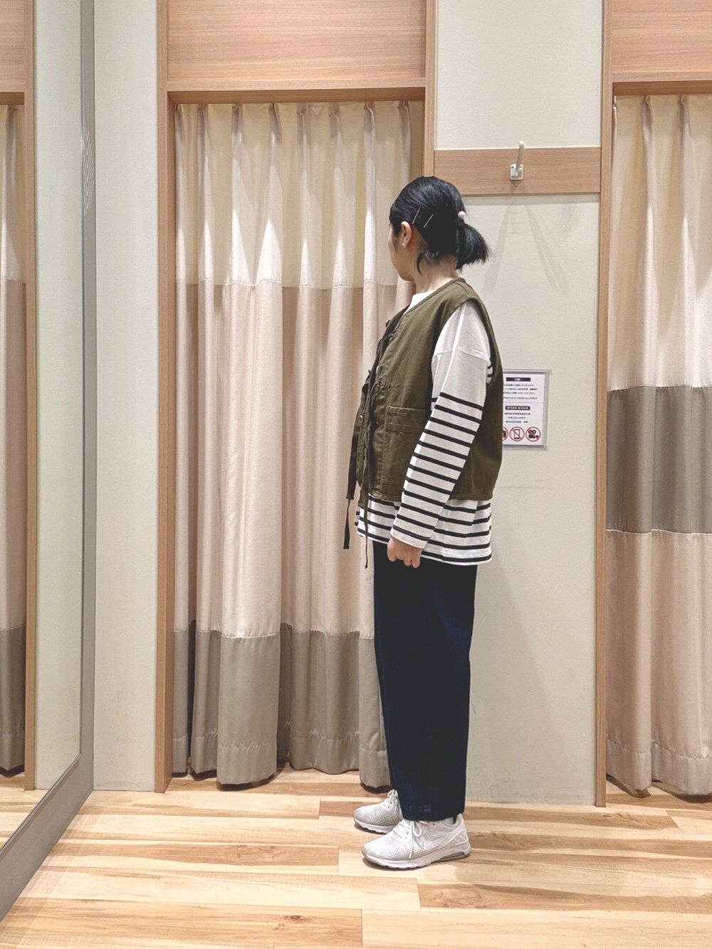 グリーン系のベスト、ブラック系のスラックス、ホワイト系のシューズを着用したレディースの春コーディネートの2枚目の写真