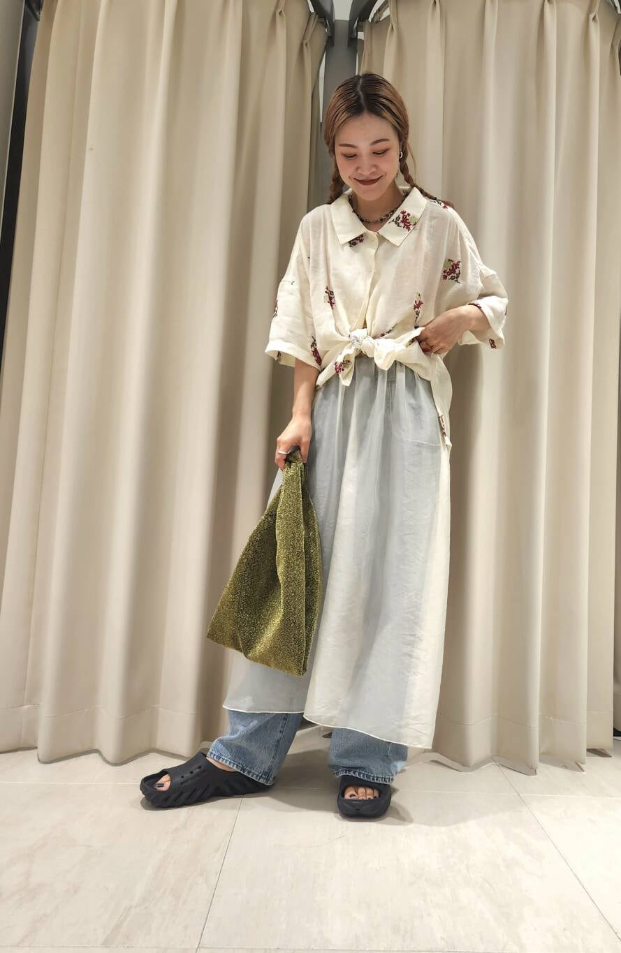 ブルー系のデニムパンツ、ホワイト系のワンピース、ゴールド系のトートバッグを着用したレディースの夏コーディネートの2枚目の写真