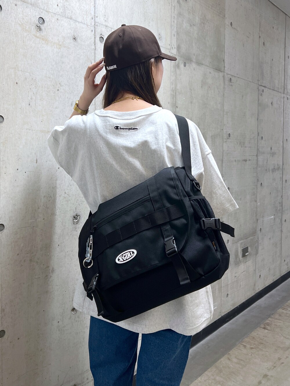 ブラック系のショルダーバッグ、グレー系のTシャツ/カットソー、ブルー系のデニムパンツを着用したレディースの春コーディネートの4枚目の写真