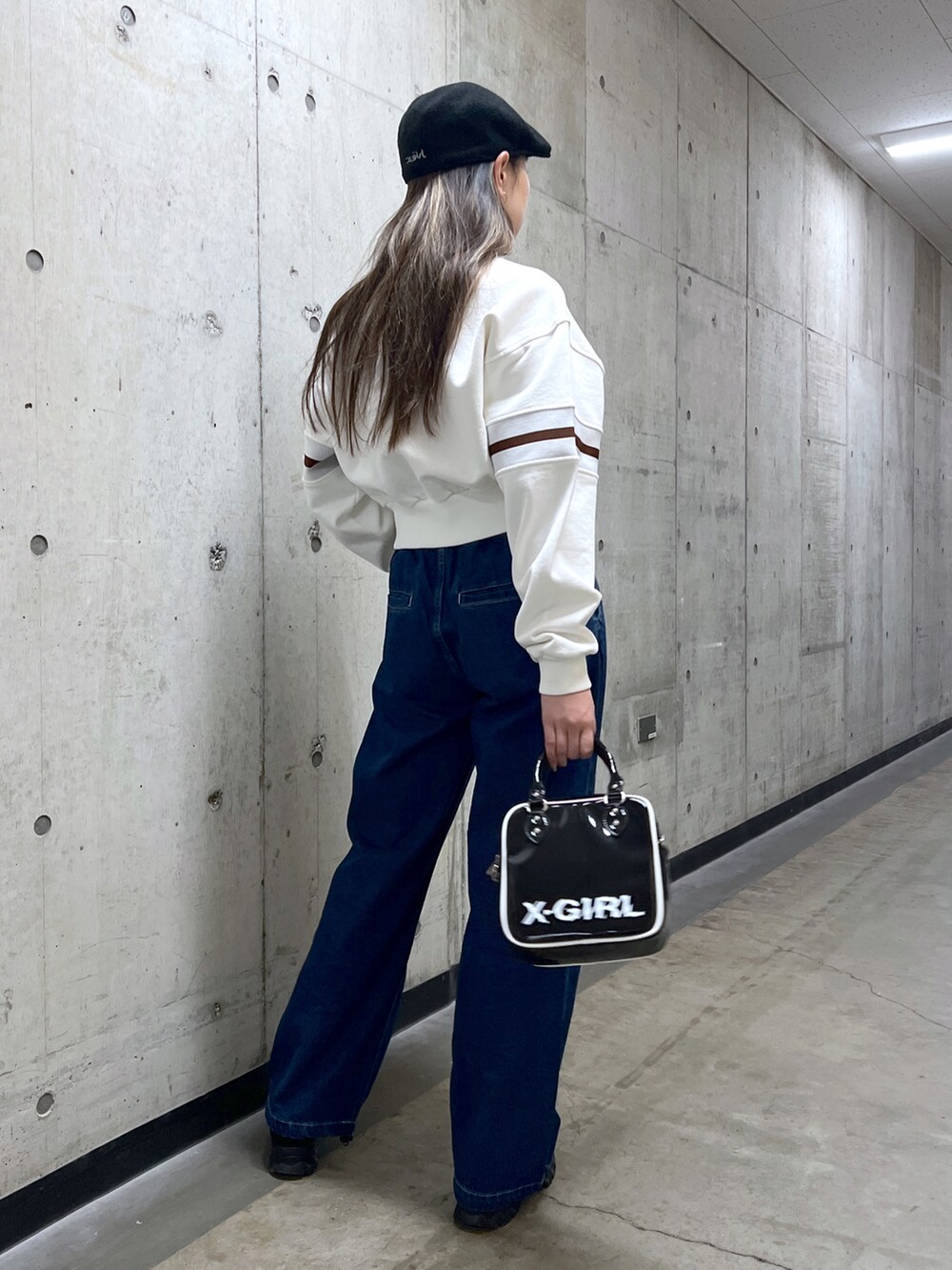 ブルー系のデニムパンツ、ホワイト系のスウェット、ブラック系のショルダーバッグを着用したレディースの冬コーディネートの3枚目の写真