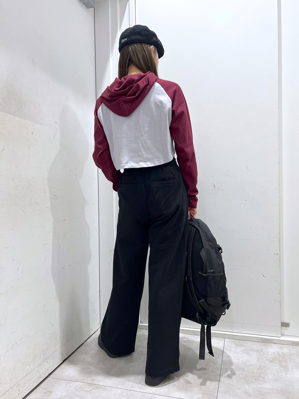 ブラック系のスウェットパンツ、レッド系のパーカー、レッド系のバックパック/リュックを着用したレディースの冬コーディネートの3枚目の写真