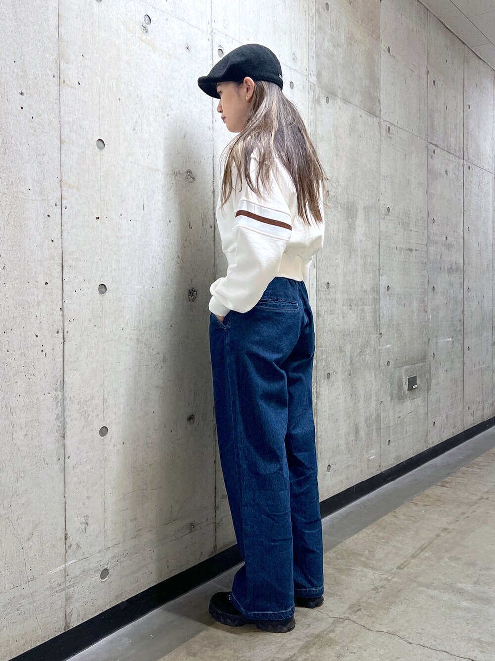 ブルー系のデニムパンツ、ホワイト系のスウェット、ブラック系のショルダーバッグを着用したレディースの冬コーディネートの2枚目の写真