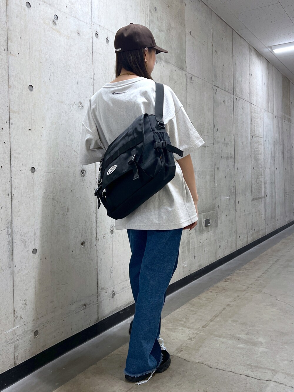 ブラック系のショルダーバッグ、グレー系のTシャツ/カットソー、ブルー系のデニムパンツを着用したレディースの春コーディネートの3枚目の写真