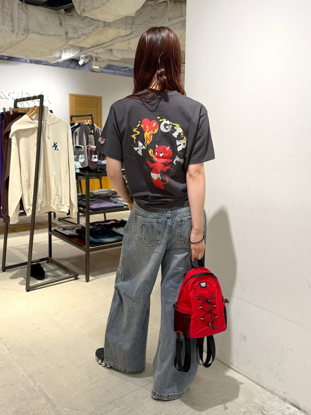 ブルー系のデニムパンツ、ブラック系のTシャツ/カットソー、レッド系のバックパック/リュックを着用したレディースの夏コーディネートの3枚目の写真