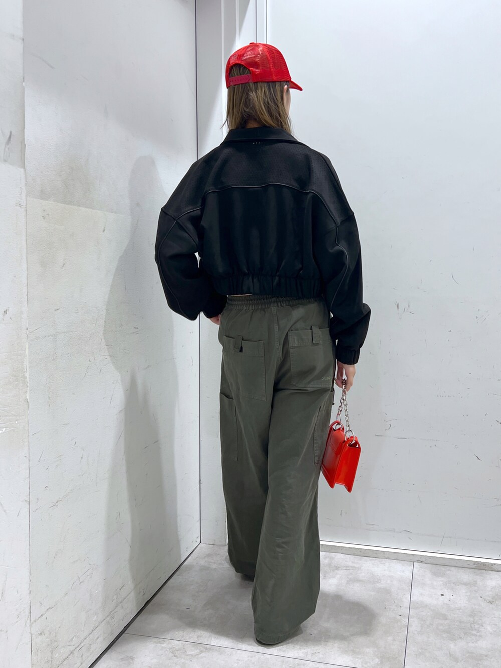 グリーン系のその他パンツ、ブラック系のブルゾン、レッド系のショルダーバッグを着用したレディースの秋コーディネートの3枚目の写真